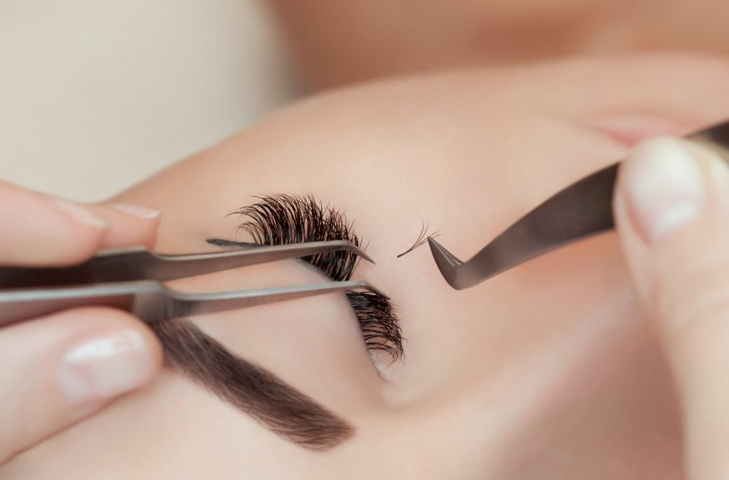 Eyelash extension procedure close up. Beautiful Woman with long lashes in a beauty salon.